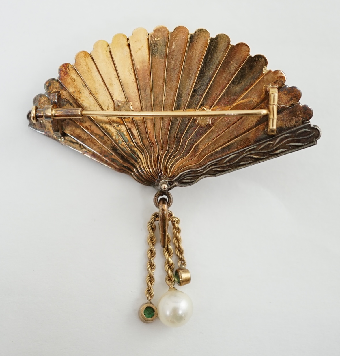 A gold (test as 15ct), emerald, rose cut diamond and enamel set brooch, modelled as a fan with applied parrot on a branch